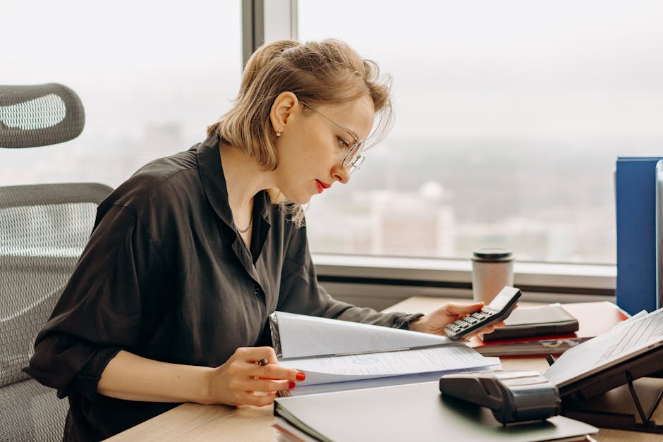 Woman accountant calculating financial documents at office desk.